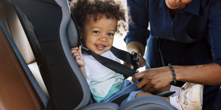 Mom goes driving with children buckled into a safe car seat.