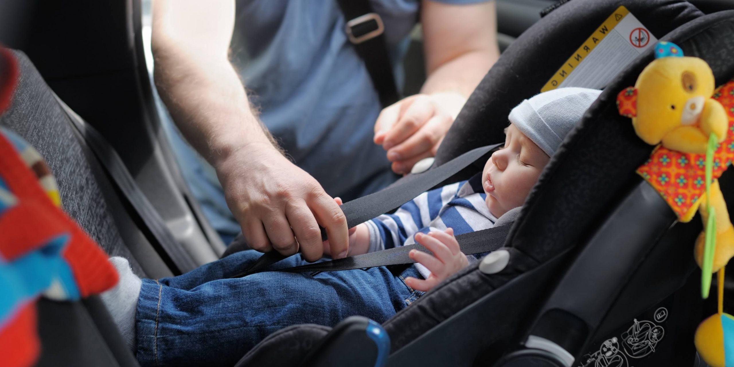 Man adjusting child car seat safety components