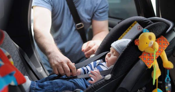 A parent fastens a baby in a baby carseat