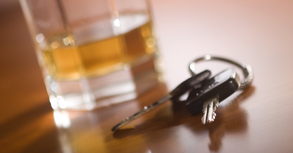 Close-up of a glass of whiskey and a pair of car keys on a wooden table